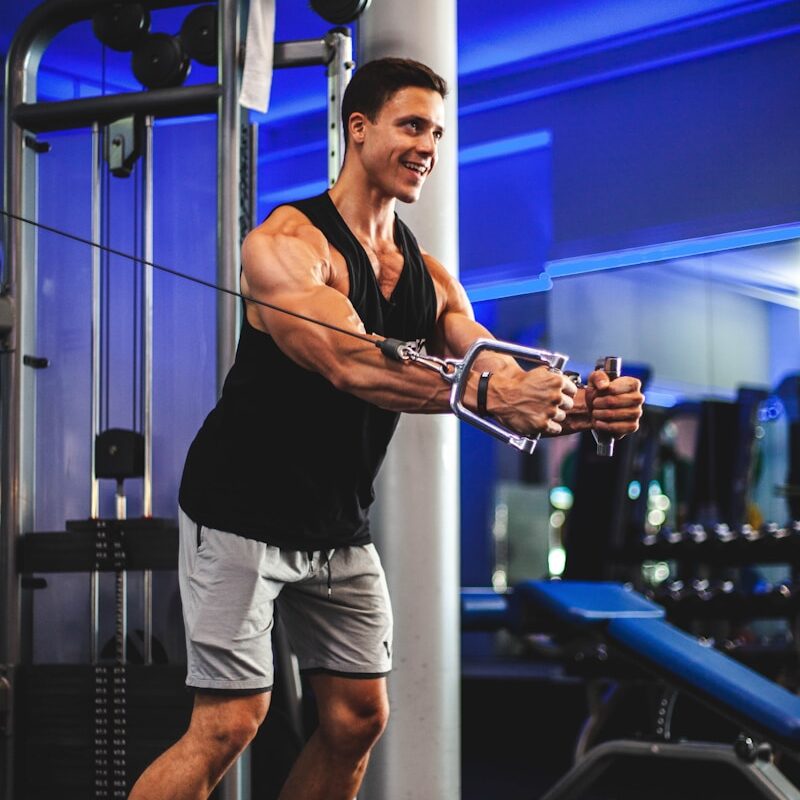 man in black tank top and gray shorts holding black smartphone